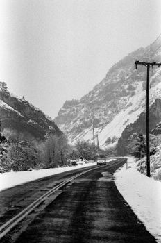 A captivating black-and-white photo of a snowy road through the mountains.