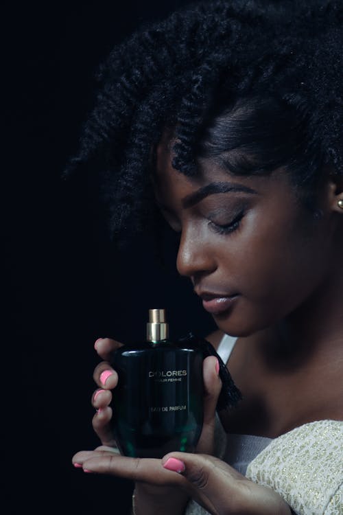 Close-Up Shot of an Afro-Haired Woman Holding a Perfume Bottle