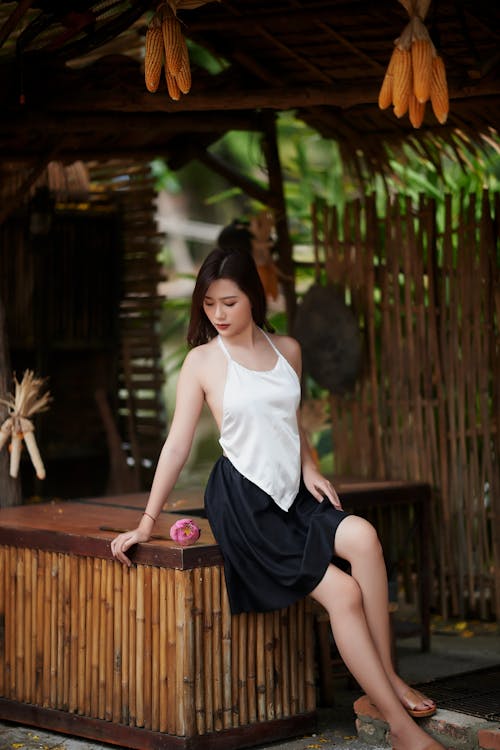 A Woman in White Tank Top Sitting on a Wooden Table Top