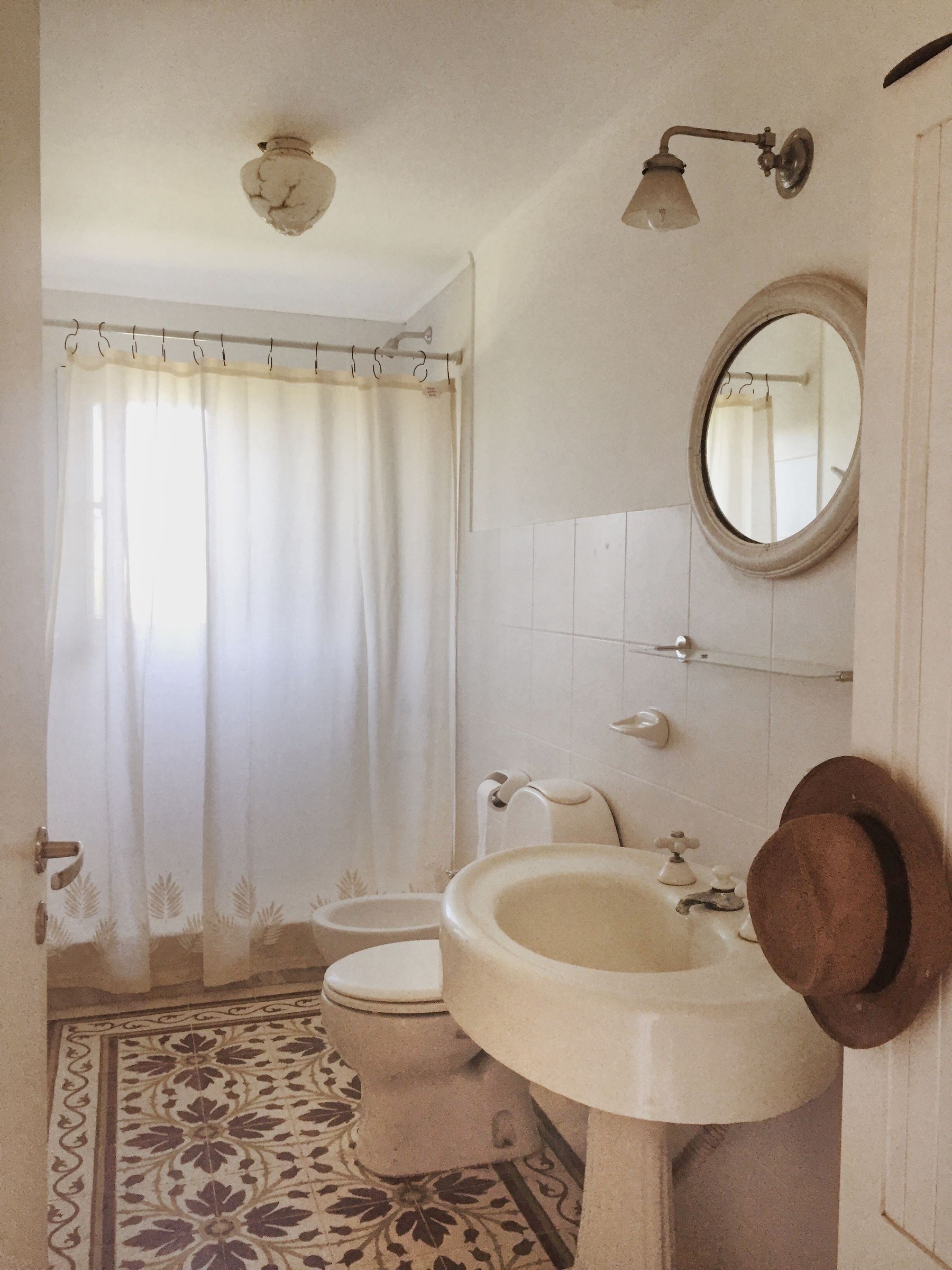 Vintage-style bathroom with floral patterned tile and round mirror