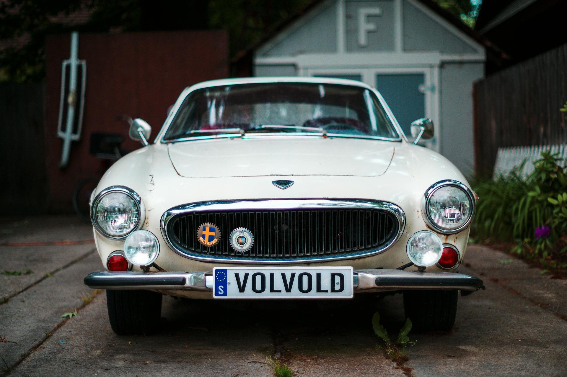 Front view of a vintage Volvo parked in a driveway, showcasing retro charm.