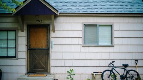 Front view of a house with a vintage bicycle and a shovel, showcasing a quaint suburban exterior.