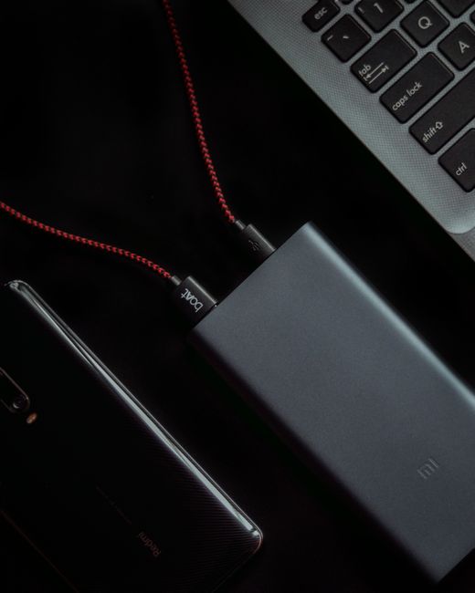 A close-up shot showcasing a laptop, smartphone, and power bank connected by cables, highlighting tech connectivity.