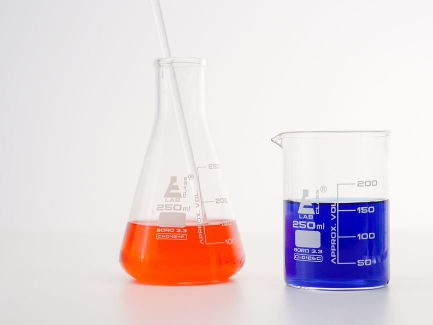 Erlenmeyer flask and beaker with vibrant liquids for science research.