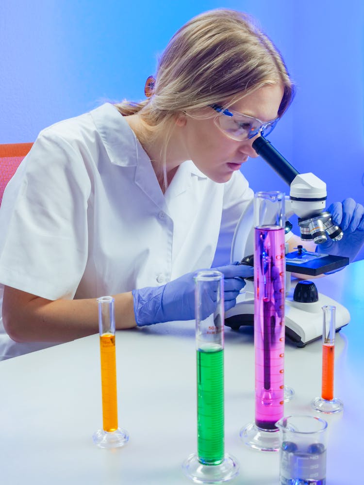 A Woman Examining A Microscope Slide