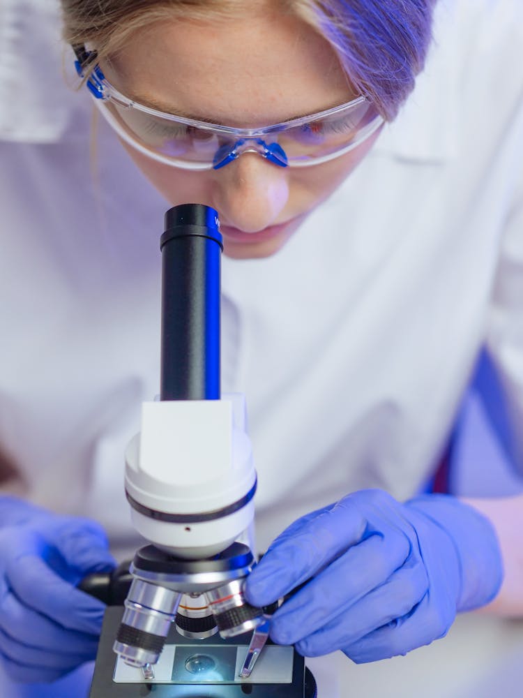 A Woman Examining A Microscope Slide