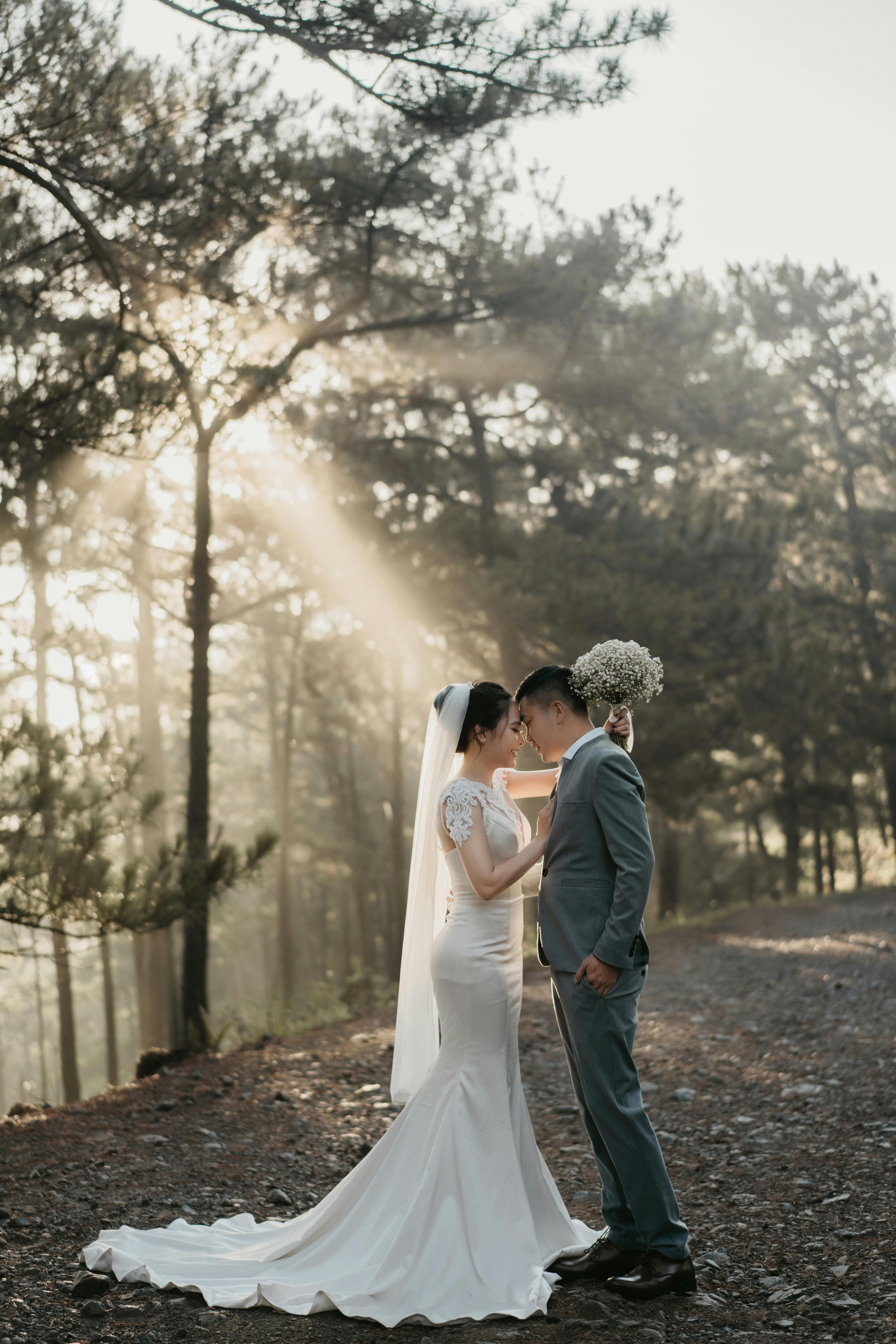 A romantic wedding photoshoot in a Vietnamese forest with a bride and groom sharing a tender moment.