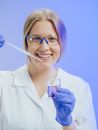 Woman in White Coat Smiling while Doing an Experiment