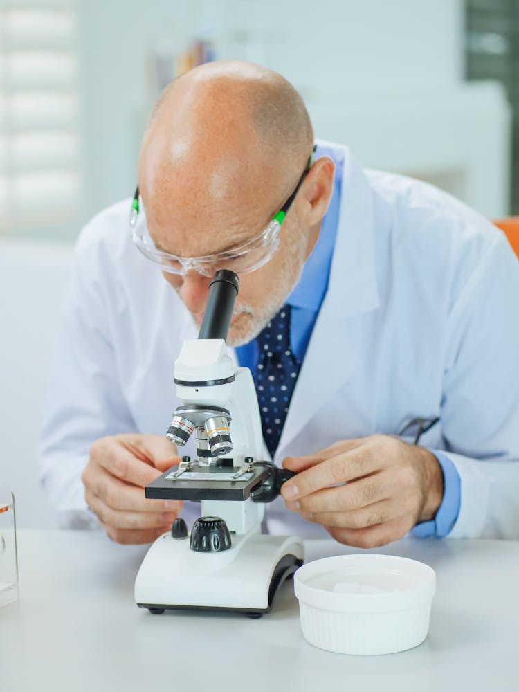 A Man Examining A Microscope Slide