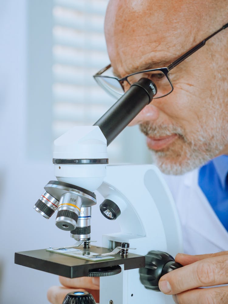 A Man Examining A Microscope Slide