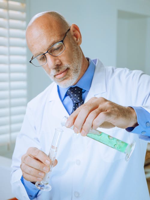 Free A Man in White Coat Doing an Experiment Stock Photo