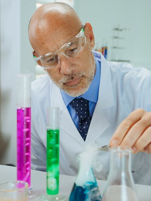 Free A senior scientist conducts experiments in a modern laboratory with colorful chemicals. Stock Photo