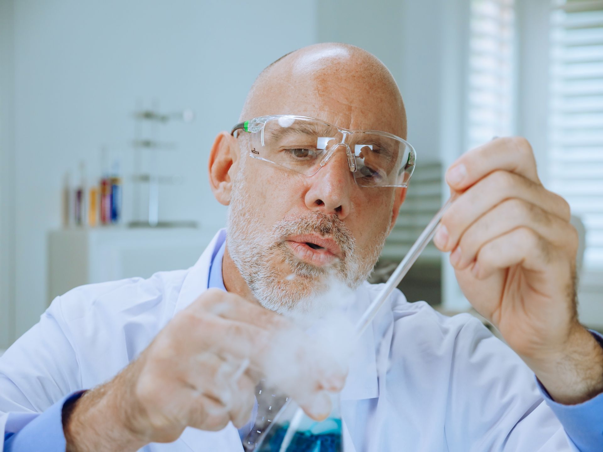A scientist in a lab coat examines chemical reactions in a laboratory setting.