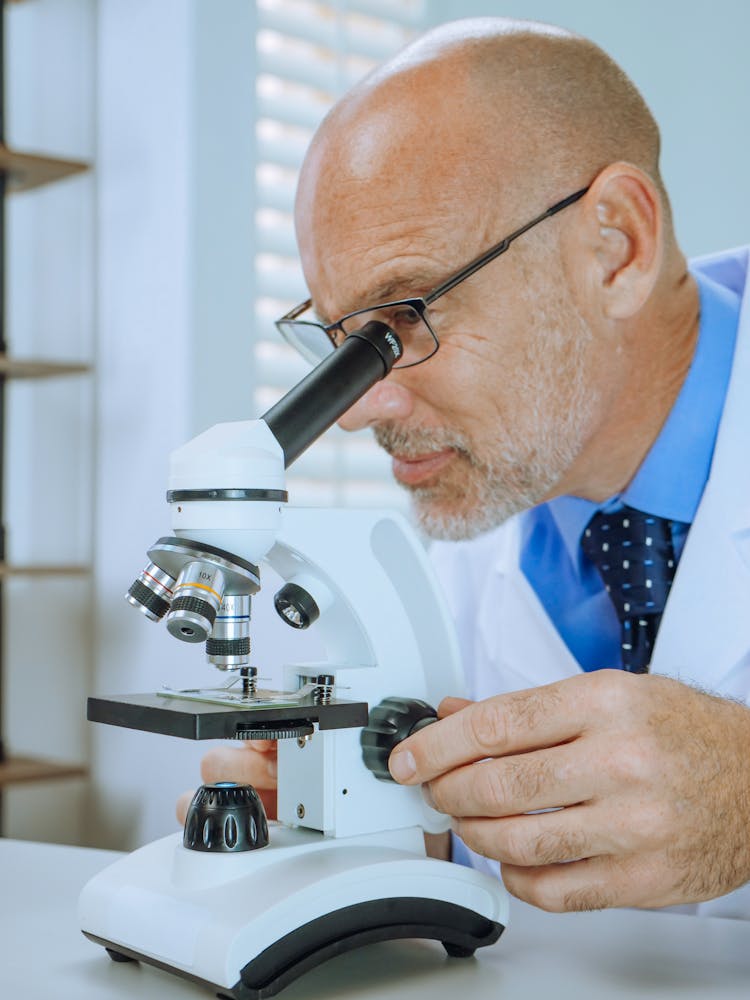 A Man Examining A Microscope Slide