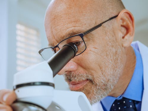 Close-Up View of A Man Examining a Microscope Slide