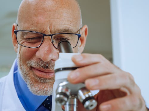 Close-Up View of a Man Examining a Microscope Slide