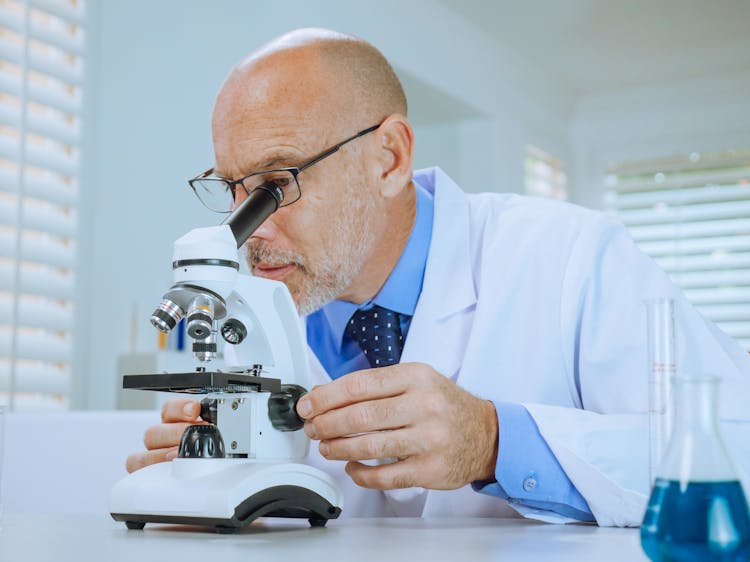 A Man Examining A Microscope Slide