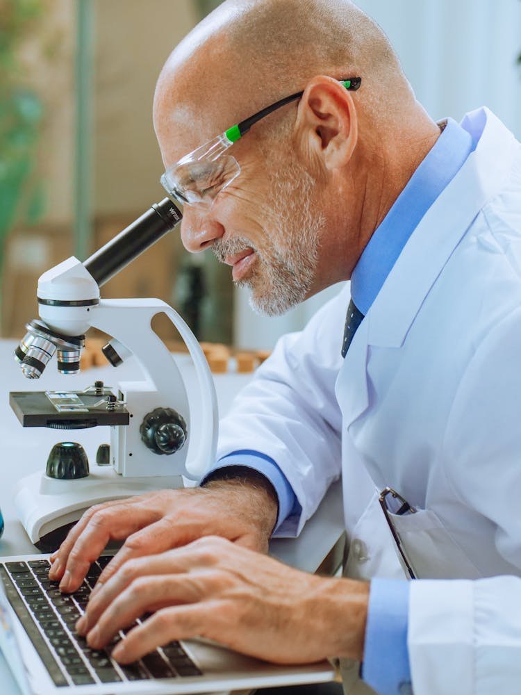 A Man Examining A Microscope Slide