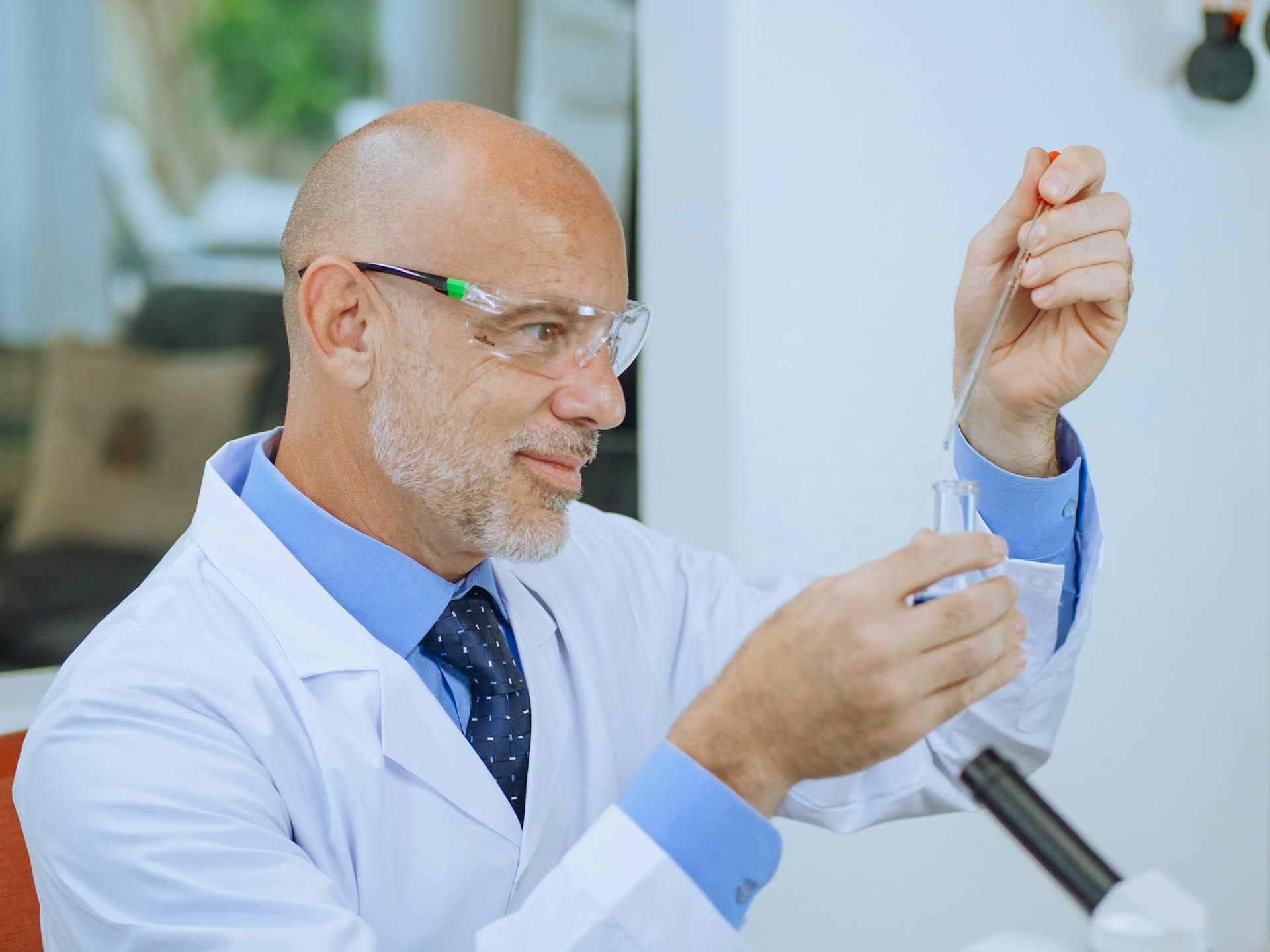 Male scientist using pipette in laboratory setup, conducting a research experiment.