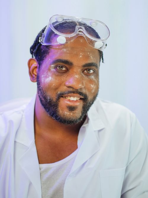 Free Cheerful scientist wearing a lab coat and safety goggles, smiling in a laboratory setting. Stock Photo