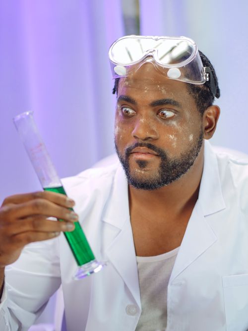 Free Scientist in lab coat examines green liquid in graduated cylinder with surprised expression. Stock Photo