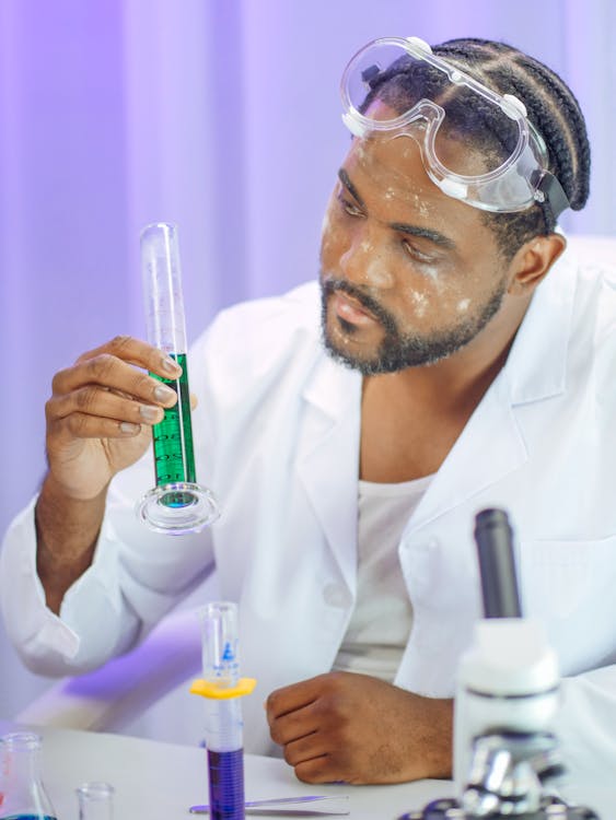 Man in White Coat Holding a Graduated Cylinder