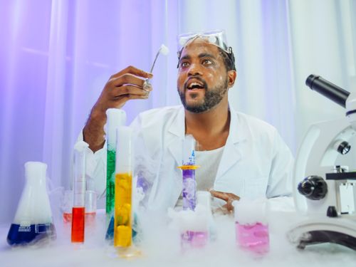 Free Scientist in white lab coat conducting colorful experiment with glassware and microscope. Stock Photo