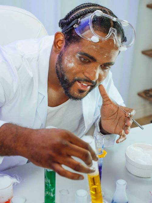 Free Scientist in lab coat conducting chemical experiment with colorful liquids. Stock Photo