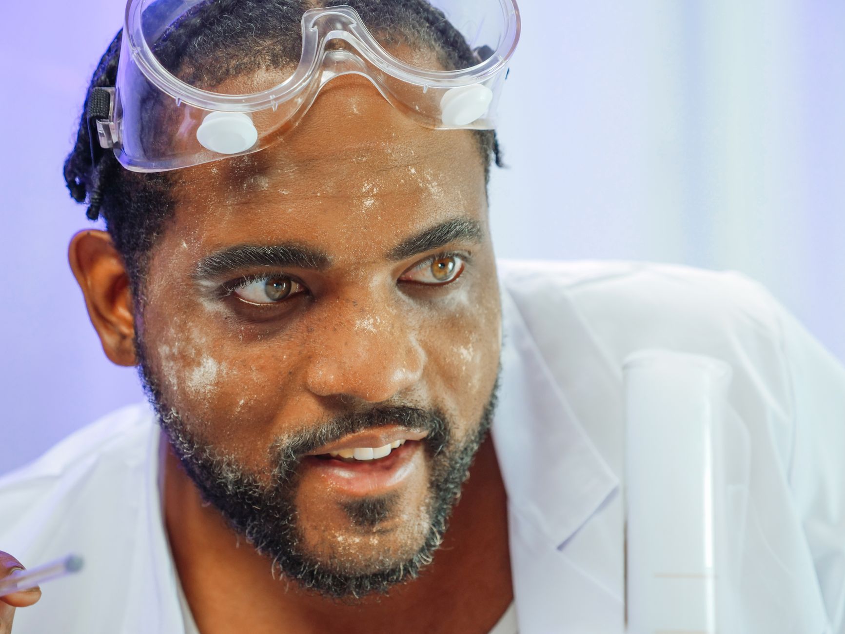 Close-up of a scientist in a lab coat conducting an experiment with glassware.