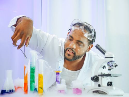Free A scientist in a lab coat working with colorful liquids in a laboratory setting. Stock Photo