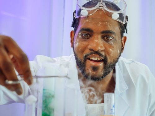 Free A smiling chemist examines a chemical reaction in a modern lab. Stock Photo