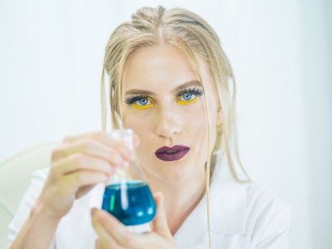 Woman scientist conducting an experiment with blue liquid in laboratory glassware.