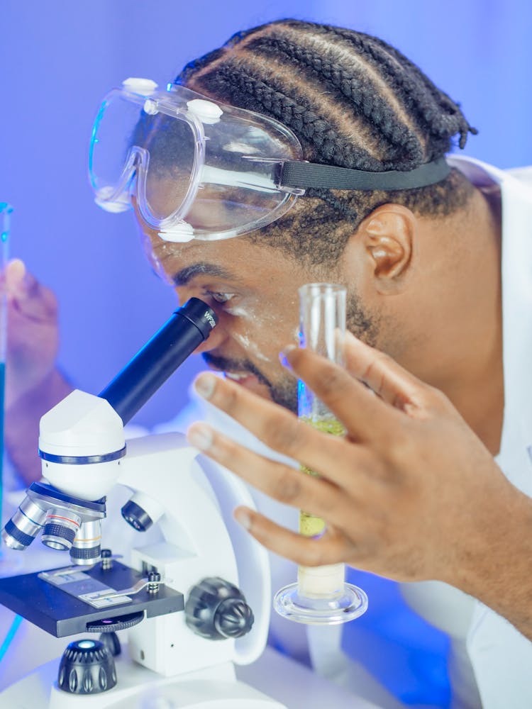 A Man Examining A Microscope Slide