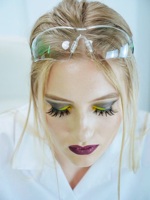 Free Portrait of a woman with makeup and safety goggles in a lab setting. Stock Photo
