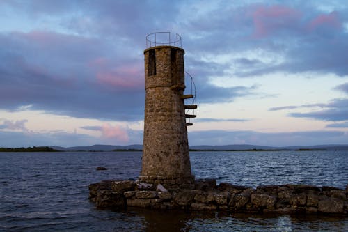 Concrete Lighthouse near Ocean under the Cloudy Sky