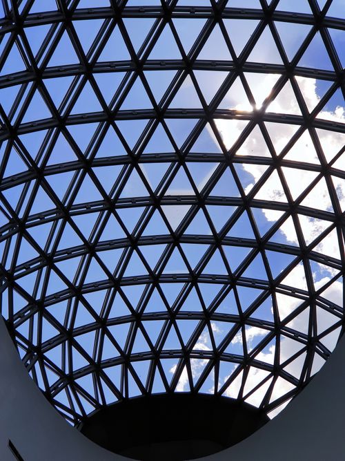 Free Geometric glass dome against a bright blue sky with clouds Stock Photo