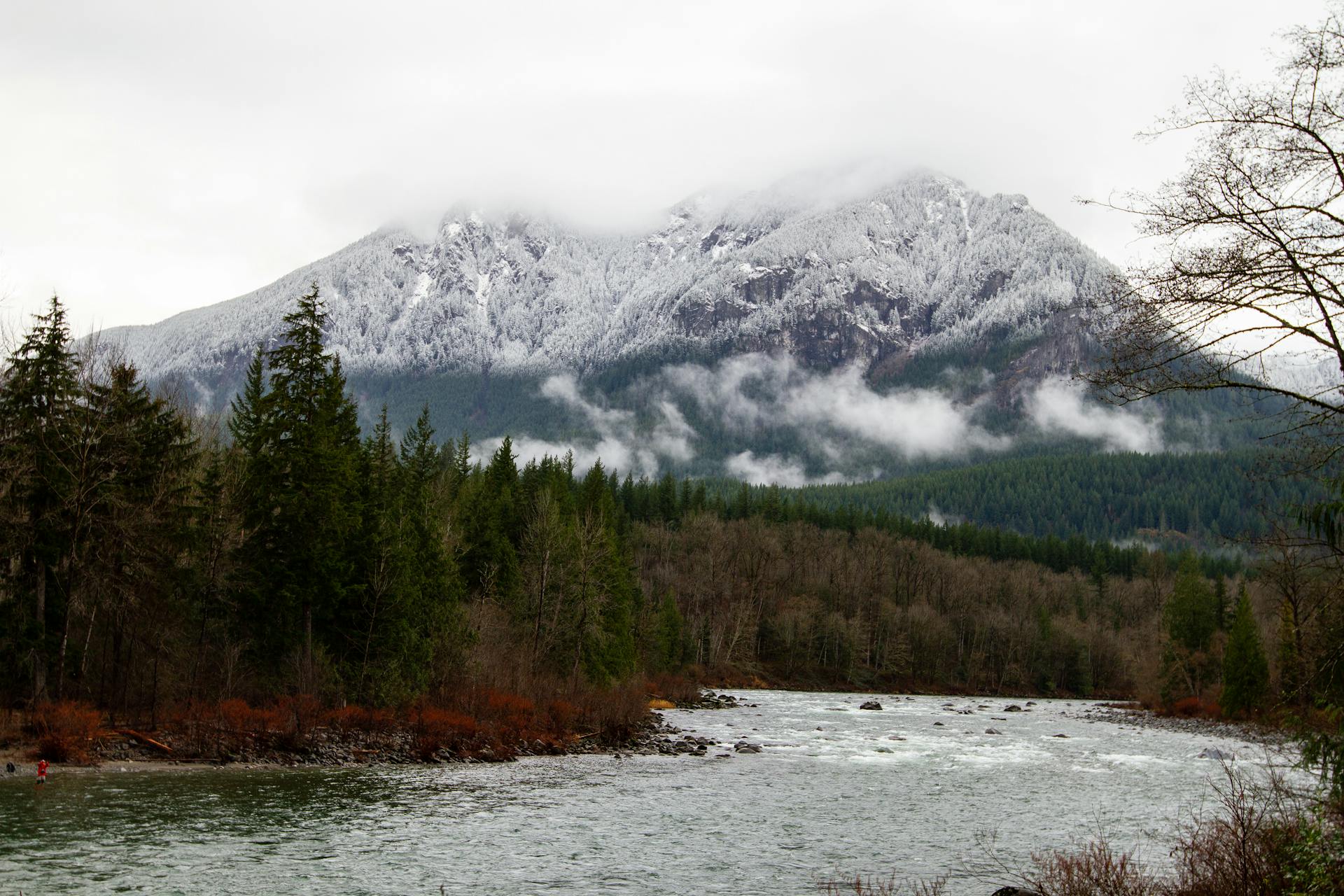 Breathtaking view of the Snohomish River flowing through a forested landscape with snow-capped mountains in Washington.