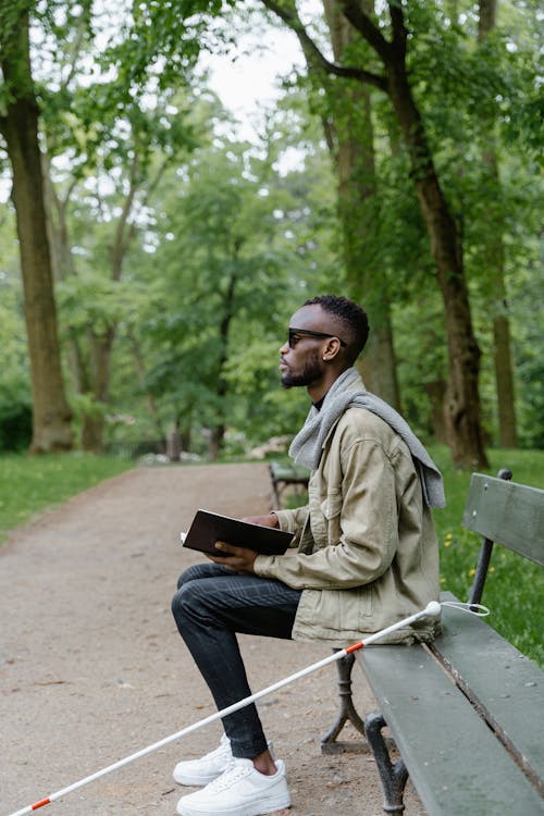 Man Sitting on Bench While Holding a Book