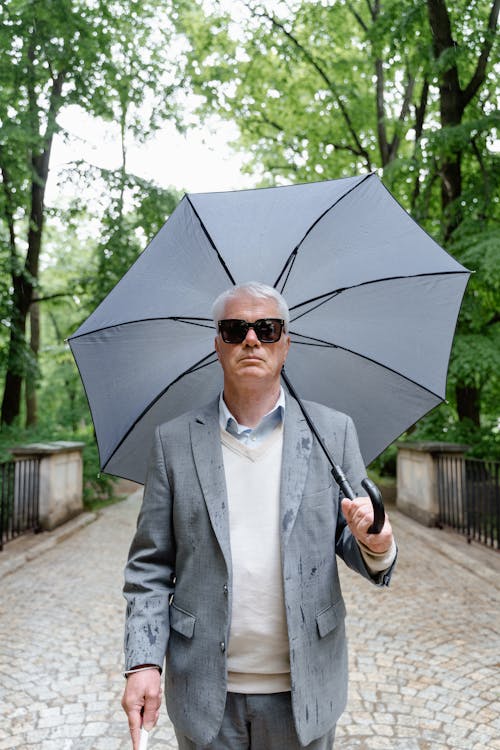 Photo of a Man in Gray Suit Jacket Holding an Umbrella