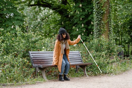 Woman Standing Up While Holding a White Cane