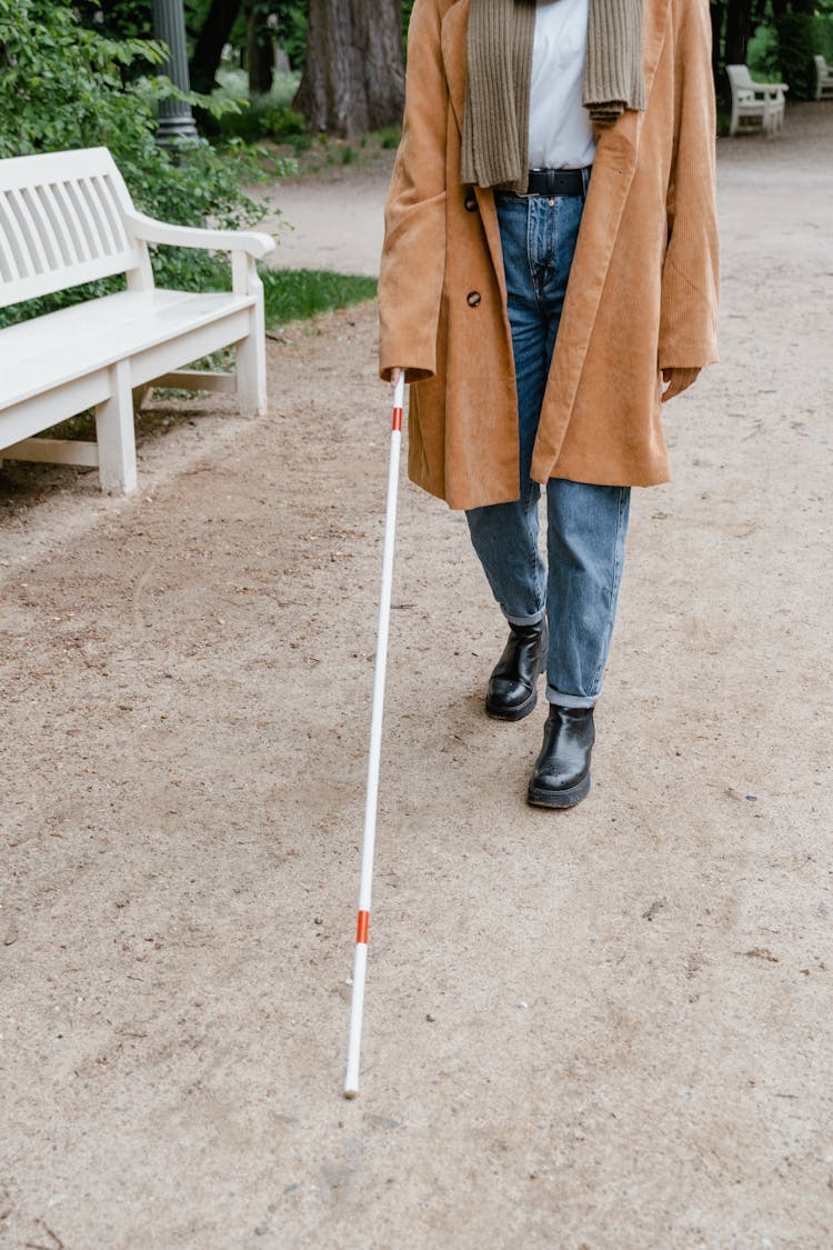 A Person In Brown Coat Holding A Walking Stick 