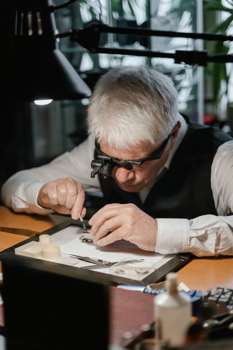 A Gray Haired Man Repairing A Watch 