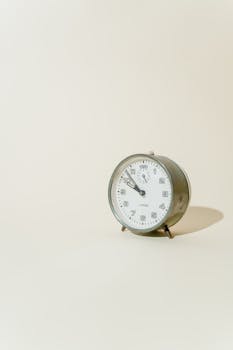 Close-up of a vintage analogue alarm clock on a neutral white surface.