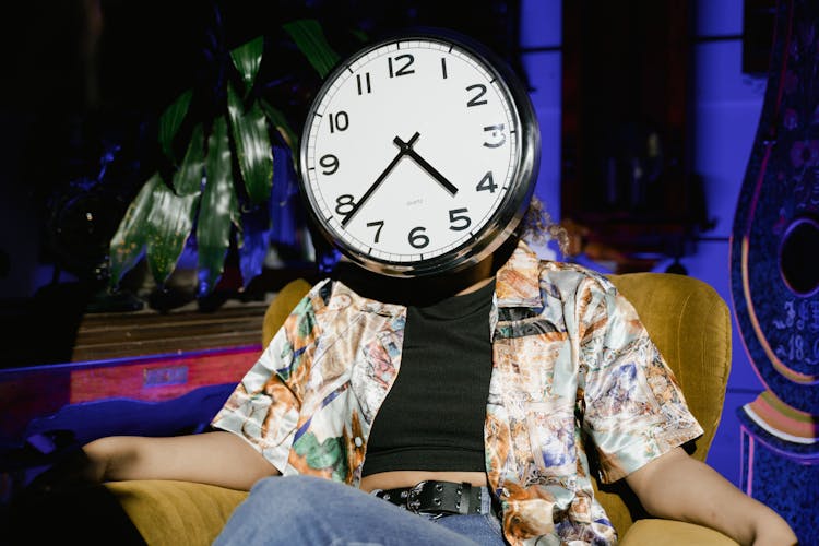 A Round Wall Clock Covering The Person Face 