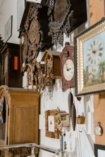 A diverse collection of vintage wooden clocks displayed on a wall, showcasing intricate designs.