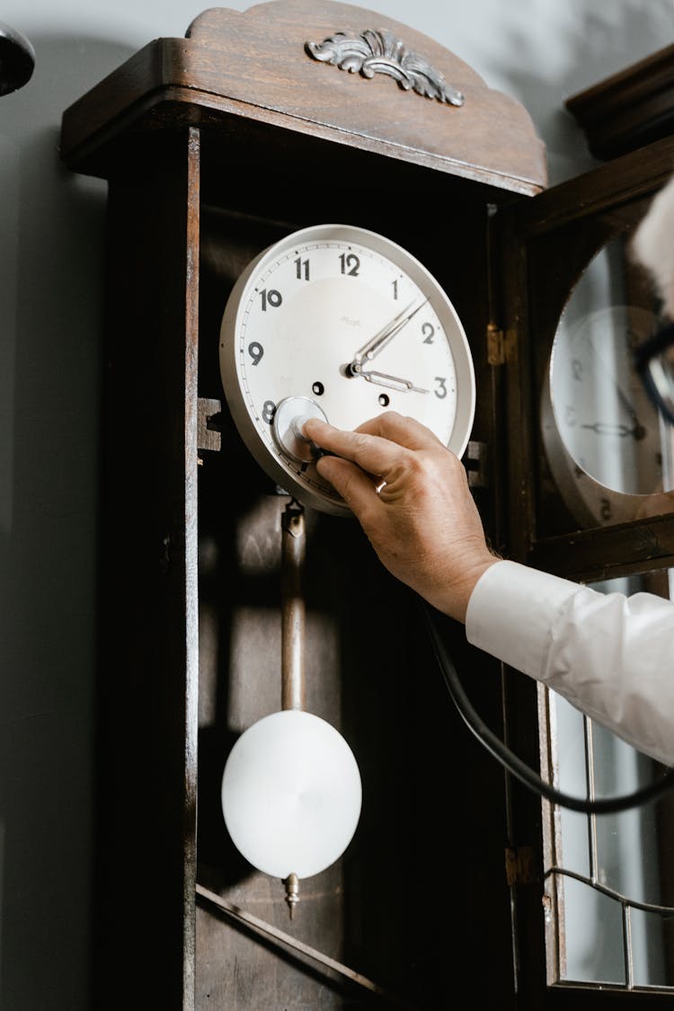 Person Checking The Vintage Wall Clock Using Stethoscope