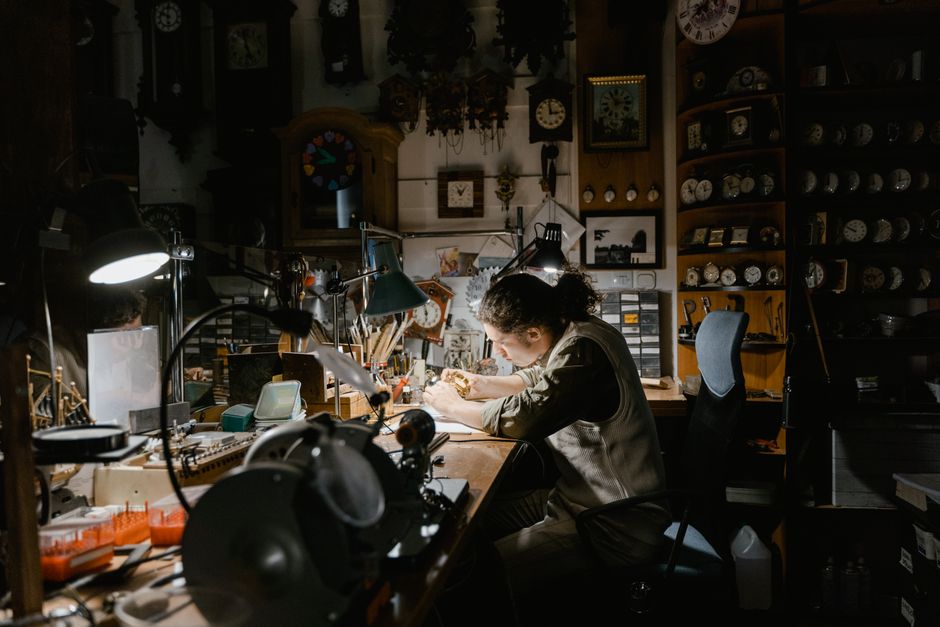 A skilled watchmaker focuses on repairing watches in a meticulously organized workshop. A skilled watchmaker focuses on repairing watches in a meticulously organized workshop.