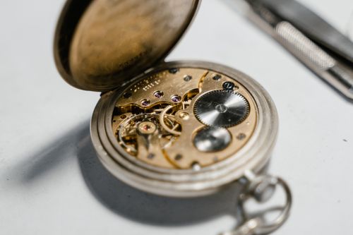 Free Detailed view of an open vintage pocket watch showcasing its intricate internal mechanism and gears. Stock Photo