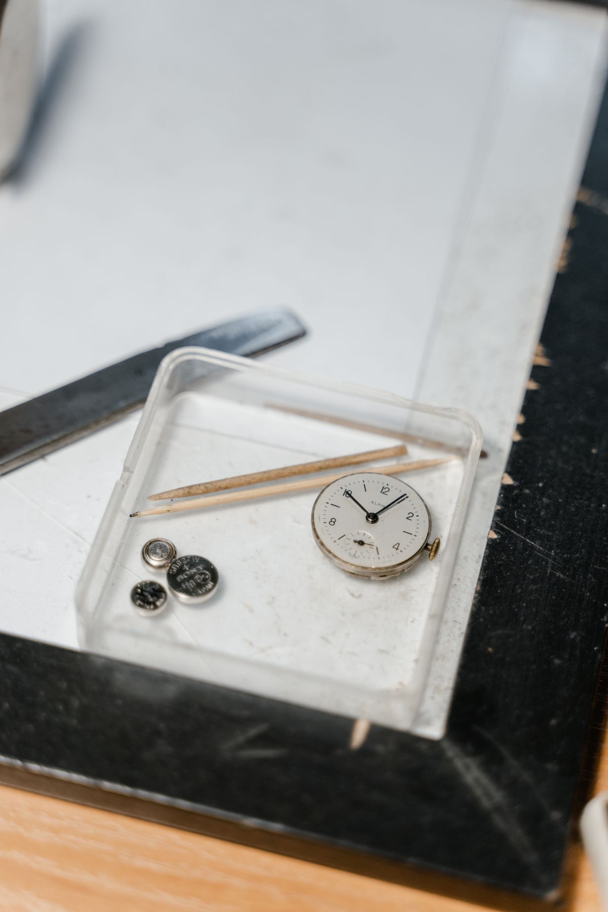 Piezas y esfera de un reloj vintage sobre la mesa de trabajo de un relojero