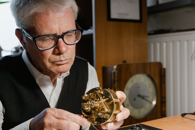 An Elderly Man Fixing A Clock